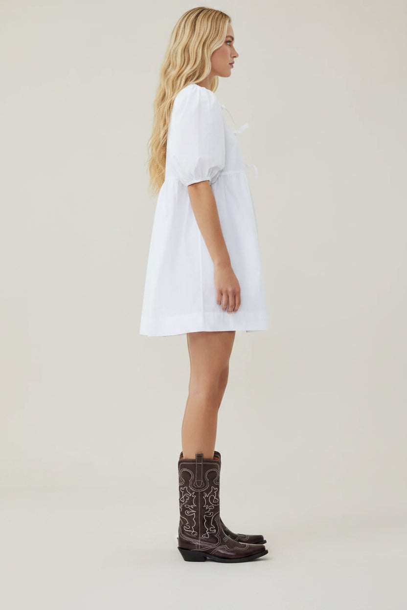 Person wearing a white dress and black rain boots on a white background