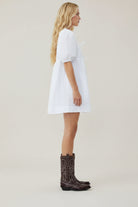 Person wearing a white dress and black rain boots on a white background