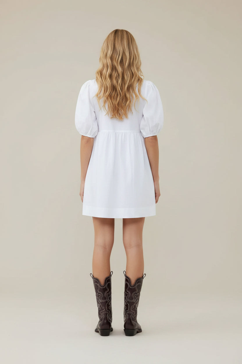 Person wearing a white dress and black cowboy boots on a white background