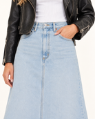 Agolde Della Denim High Rise Midi Skirt A light wash blue denim A-line skirt worn by a model, styled with a white ribbed top and a black leather moto jacket against a plain white background.