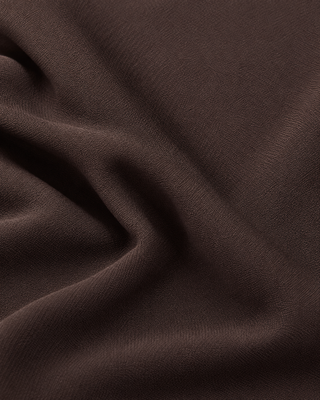 A close-up of draped dark brown fabric with soft folds and a smooth, matte texture.