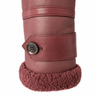 Close-up of a tall boot or shoe in dusty rose-brown faux leather with a matching fuzzy shearling-style cuff and a decorative button closure on the side.
