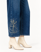 Close-up of a person wearing Paige x Disney Cinderella Rhinestone Embellished Embroidered Jeans