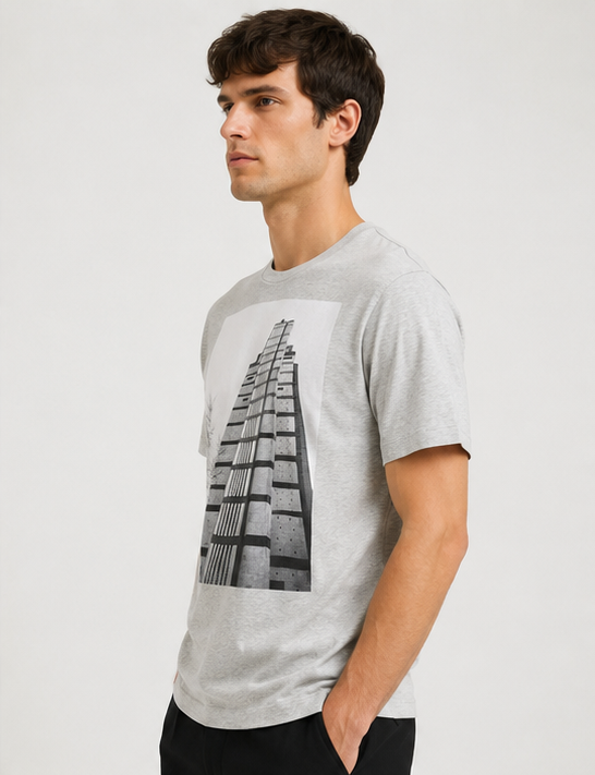 Dries Van Noten Grey Hertz Tower T-Shirt A man wearing a light gray heather crewneck t-shirt with a black and white architectural building graphic on the front, photographed against a plain light gray background.