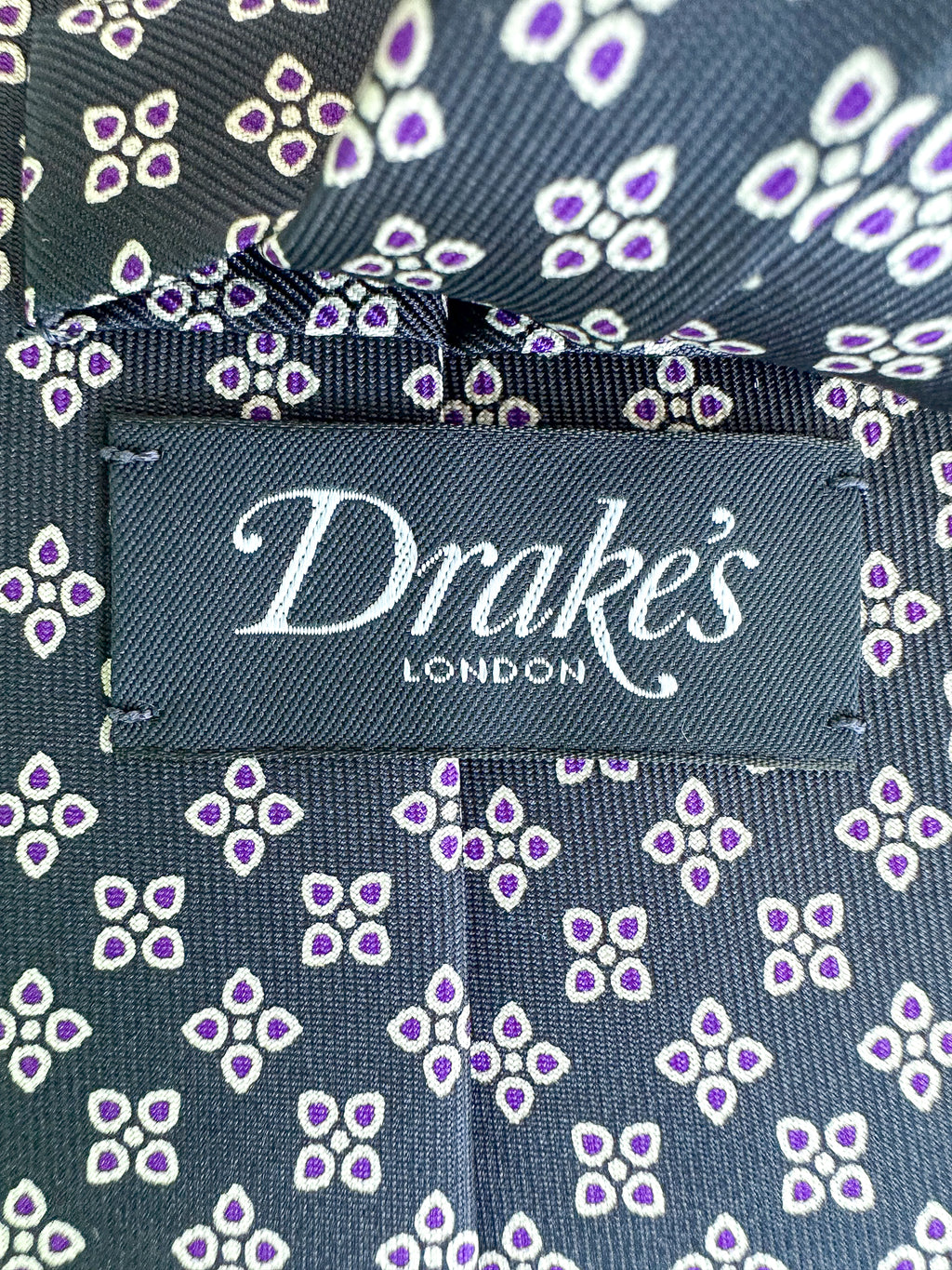 Drake's Marineblaue Seidenkrawatte mit lila Blumenblättern