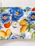 A close-up of a fabric product, likely a pouch or bag, featuring a watercolor-style floral print with blue peonies, yellow lemons, and green leaves on a white background.