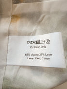 Close-up of a garment's interior care label reading 'Dry Clean Only' with material composition '65% Viscose 35% Linen' and 'Lining: 100% Cotton' on a light beige fabric background.