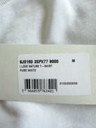 A close-up of a white garment tag attached to a white textured fabric item, showing a barcode and printed text including 'PURE WHITE' and size information.