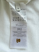 Close-up of a garment size and care label sewn onto a white fabric item, showing the brand STELLA MCCARTNEY and size M.