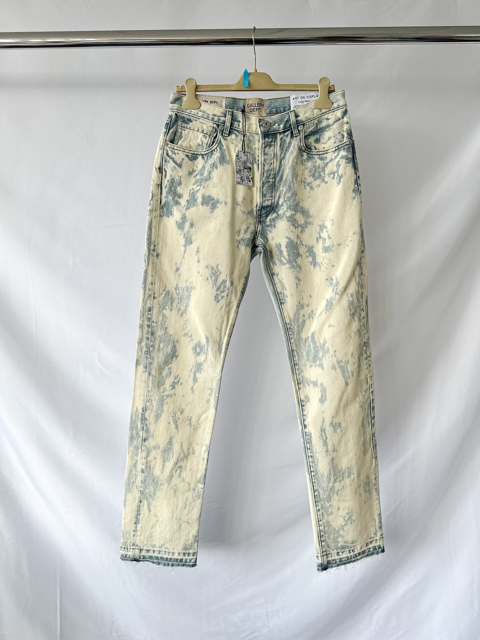 Gallery Dept Distressed Bleached  jeans on a hanger against a white background
