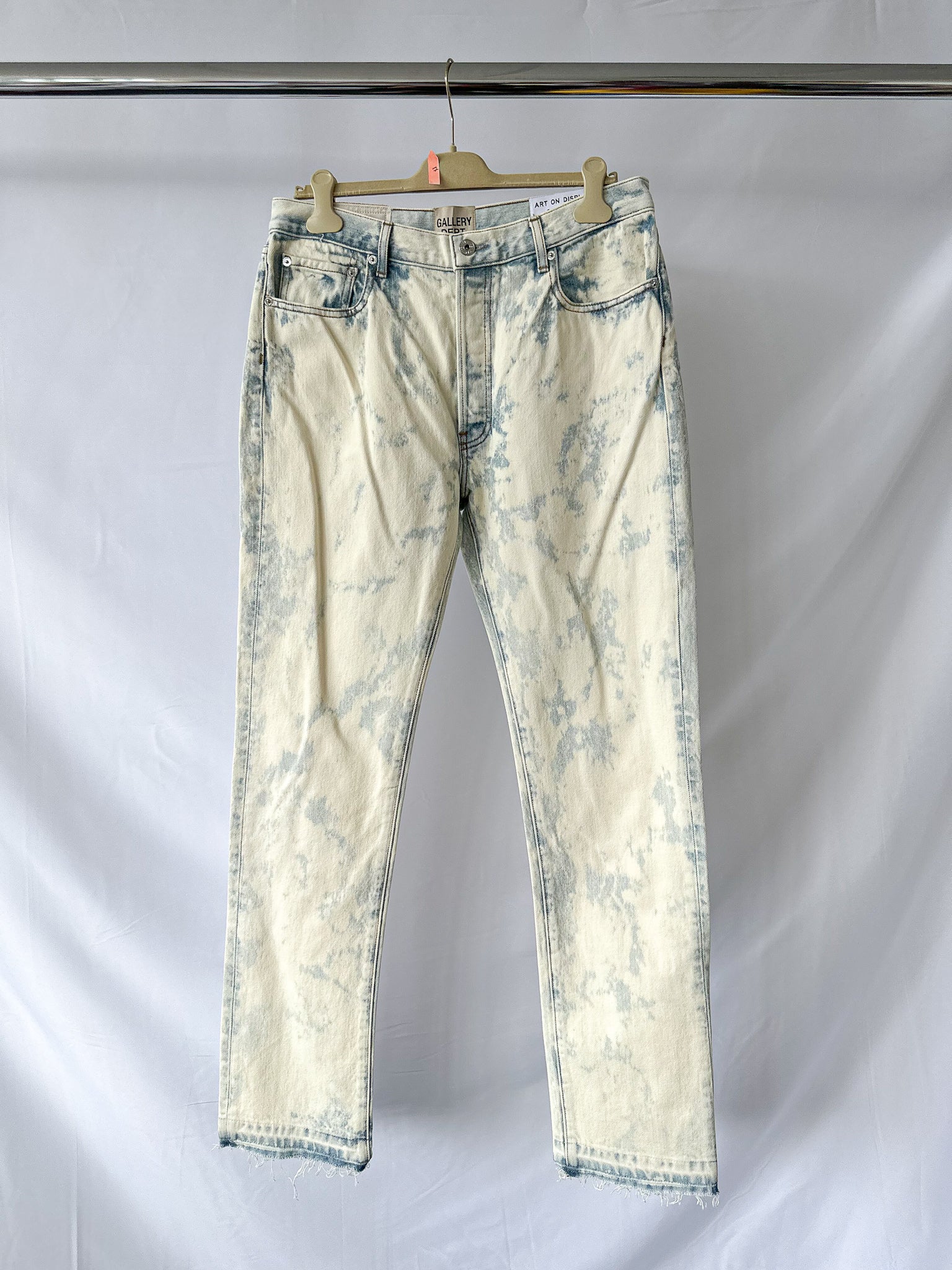 Gallery Dept White distressed jeans on a hanger against a white background