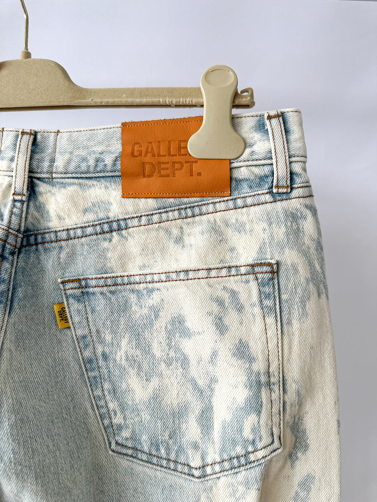 Blue acid-wash jeans on a hanger with 'Galle Dept.' label.