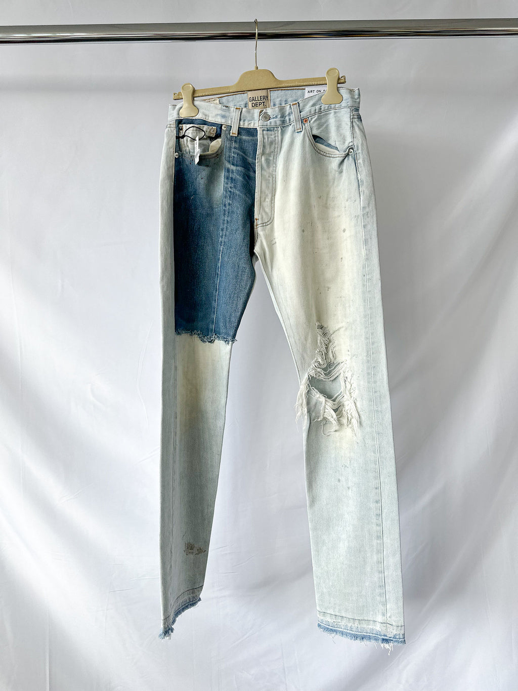 Gallery Dept Pair of light blue jeans on a hanger against a white background