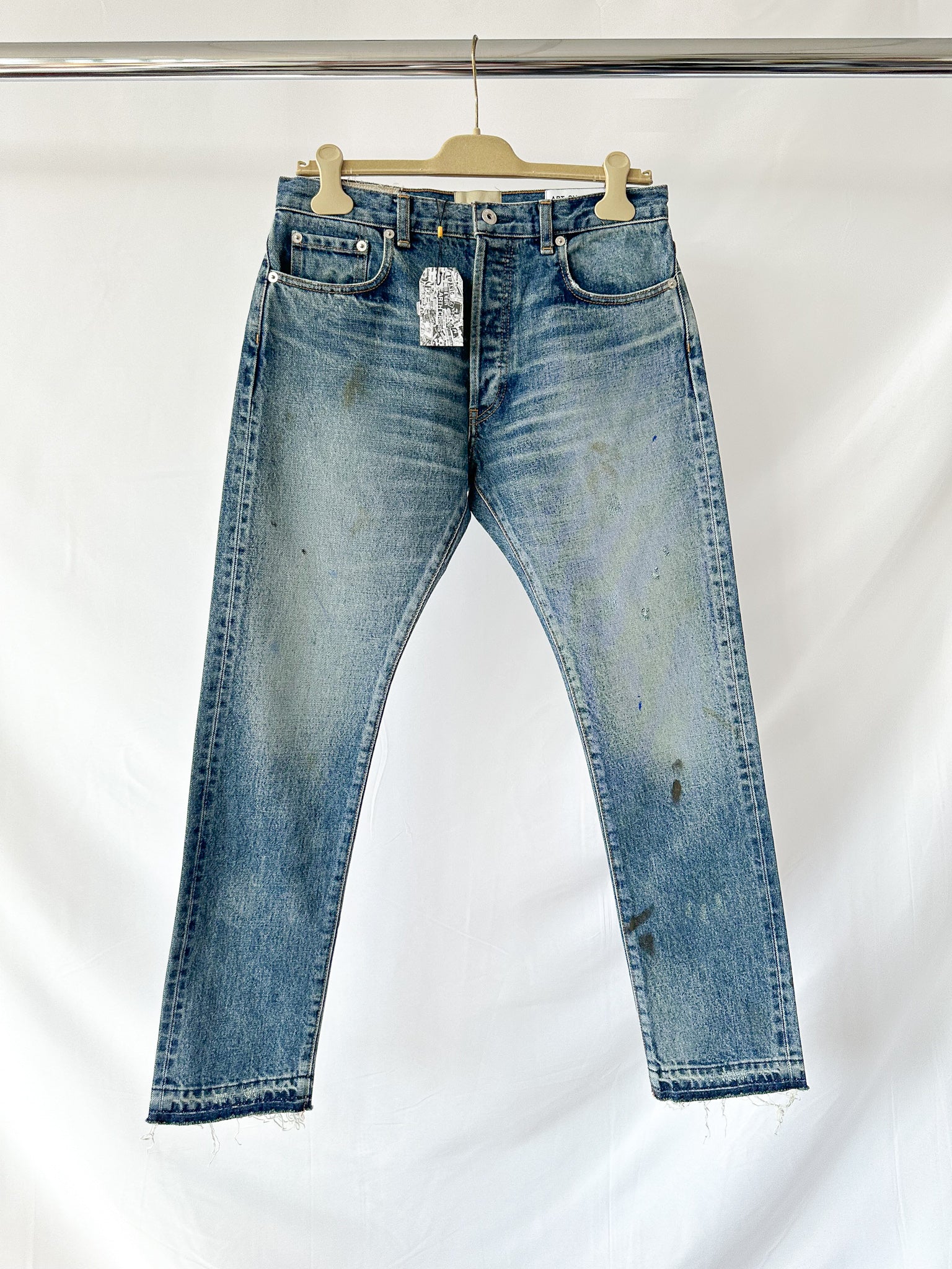 Gallery Dept Blue jeans on a hanger against a white background