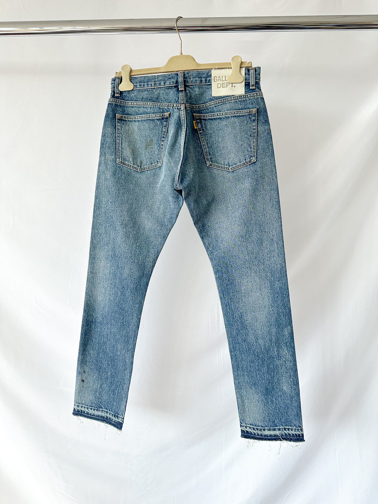 Gallery Dept Blue jeans on a hanger against a white background