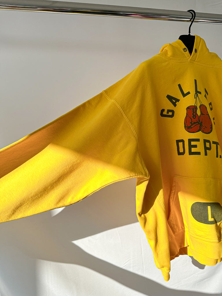 Gallery Dept Yellow hoodie with graphic design on a white background