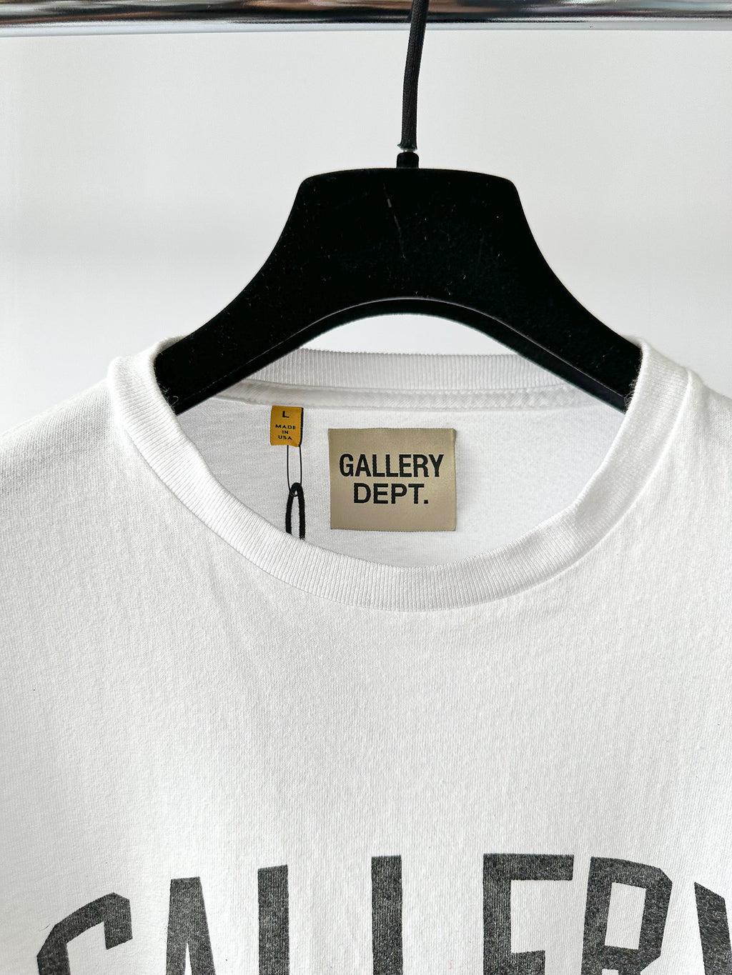 White t-shirt with 'GALLERY DEPT.' branding on a hanger against a white background