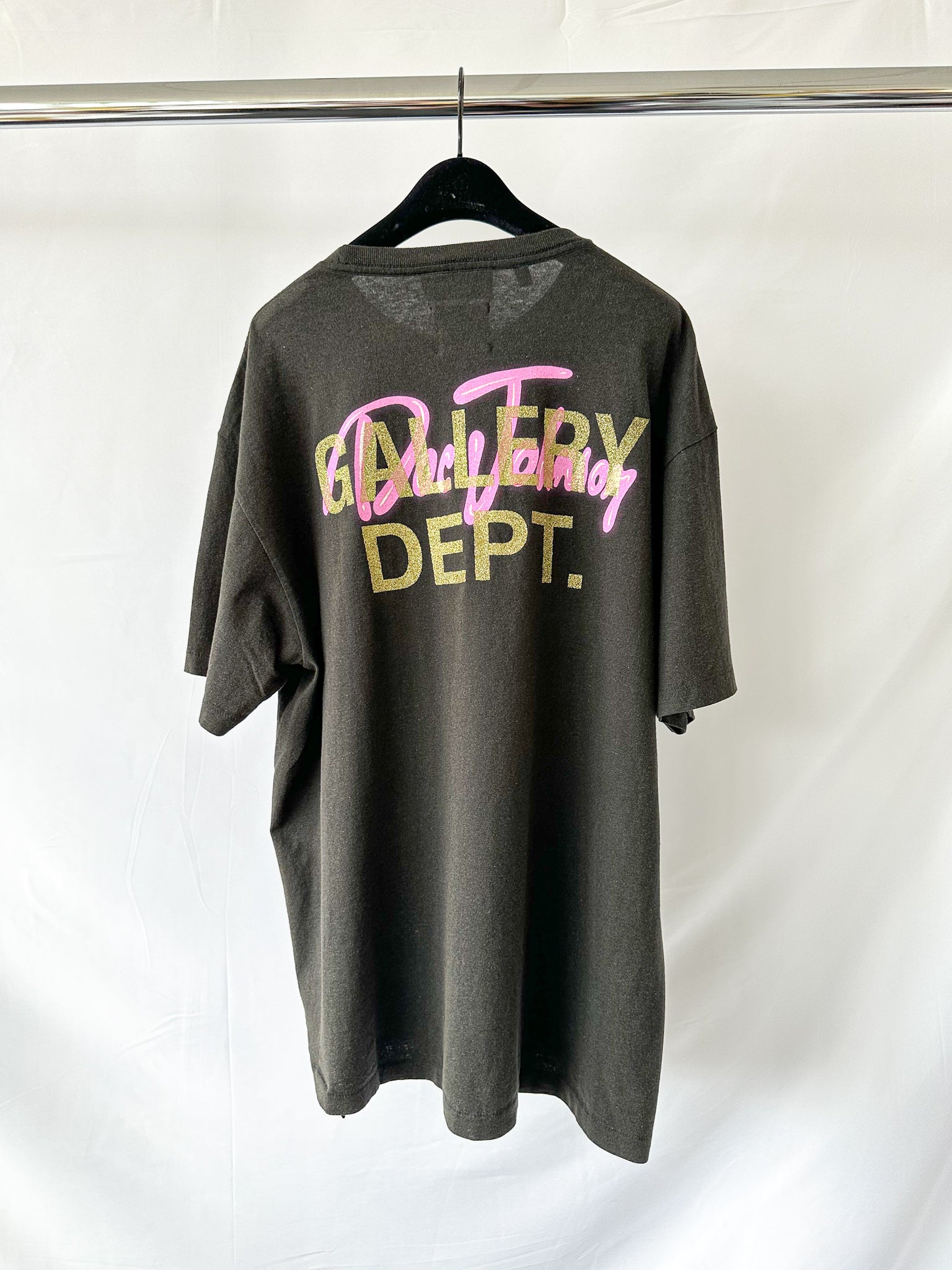 GGallery Dept gray t-shirt with colorful text on a hanger against a white background