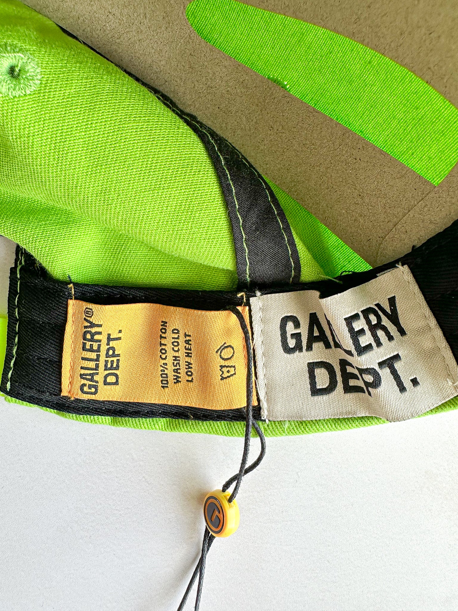 Close-up of clothing labels with 'Gallery Dept.' branding on a green and beige fabric background.