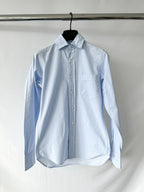 Drake's ight blue button-up shirt on a hanger against a white background