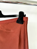 Red skirt with a black clip on a hanger against a white background