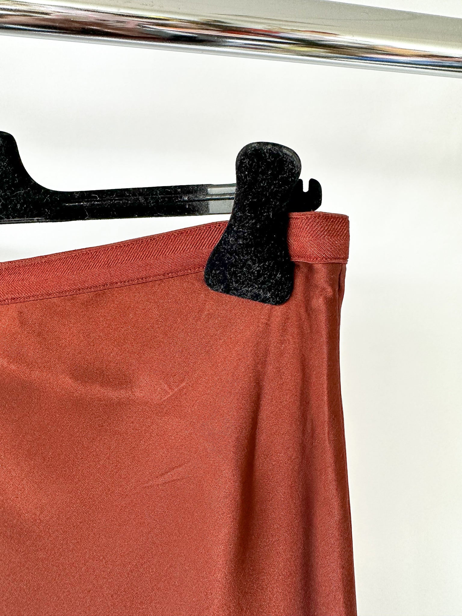 Red skirt with a black clip on a hanger against a white background