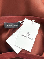 Close-up of a red fabric with 'Anine Bing' branding on a tag.