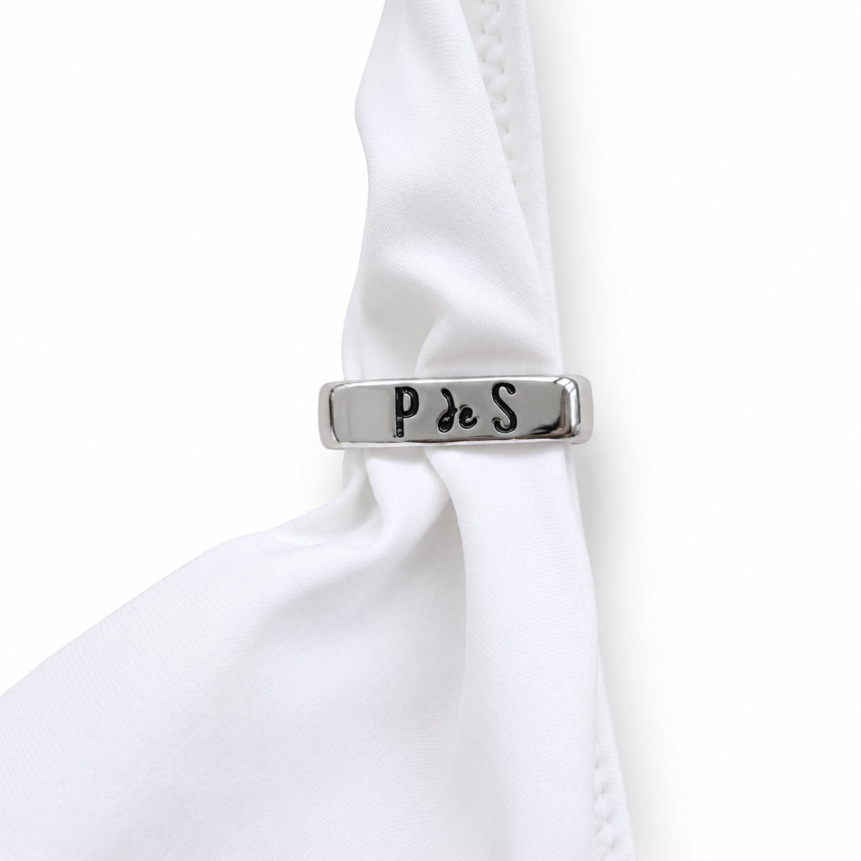 Silver cufflink with 'P de S' engraving on a white shirt sleeve.