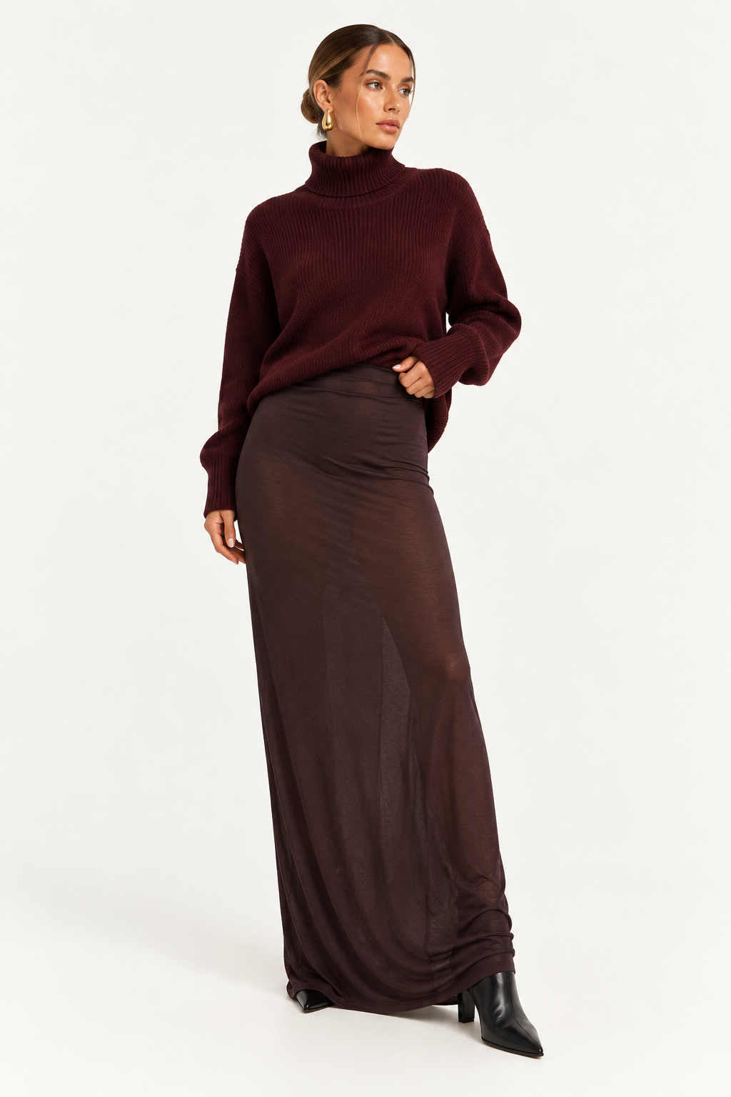 Skims Brown Sheer Modal Long Skirt A woman modeling a dark burgundy ribbed turtleneck sweater and a matching dark brown sheer maxi skirt, paired with black pointed-toe ankle boots, against a plain white studio background.