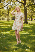 Woman wearing a floral needle & thread dress in a sunny park