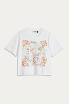 A white short-sleeve crop top t-shirt featuring a large, colorful vintage-style floral map graphic on the front, displayed flat against a light off-white background.